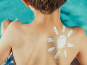 child sitting by the pool with sunscreen drawn into the shoulder representing the sun.